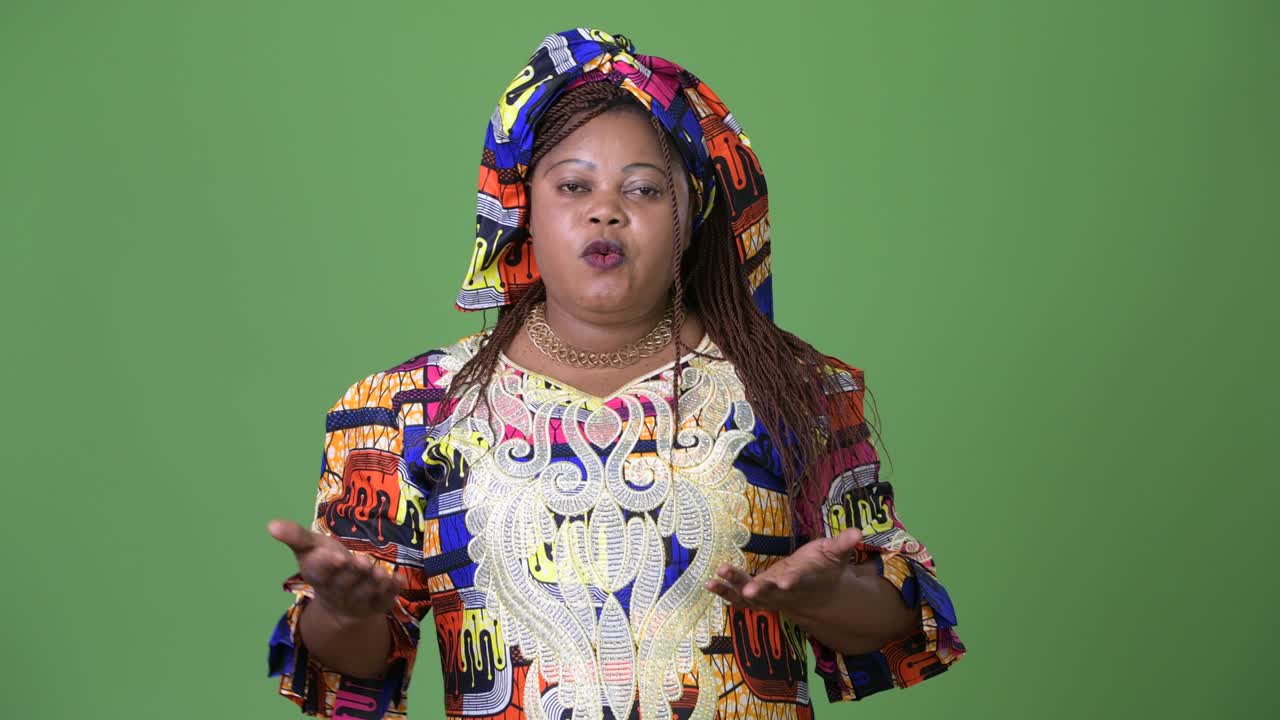 Overweight beautiful African woman wearing traditional clothing against green background