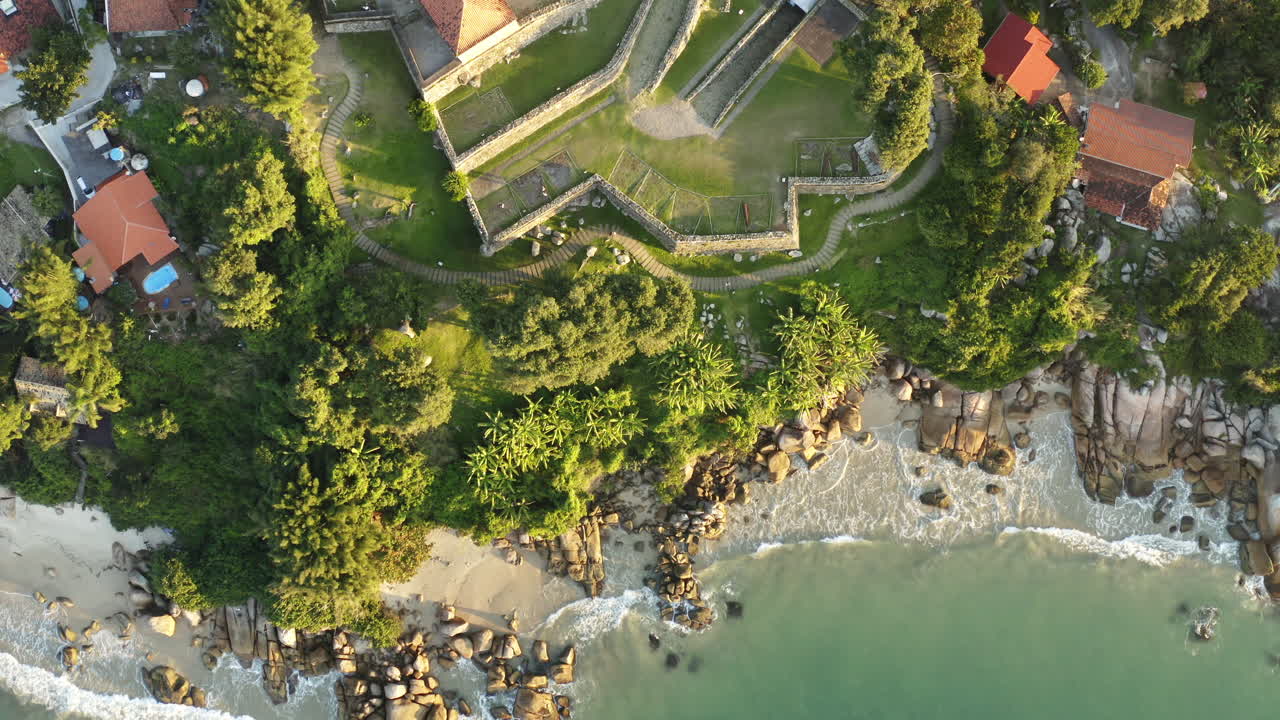 fortaleza con vista aérea de drones al atardecer, playa paradisíaca de la costa rocosa brasileña, sao jose da ponta grossa, jurere internacional, florianópolis, santa catarina, brasil
