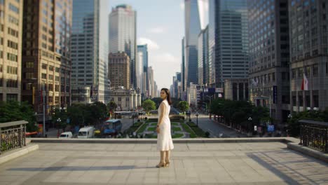 a young woman in a flowing white dress walks gracefully through a vibrant urban square surrounded by skyscrapers.