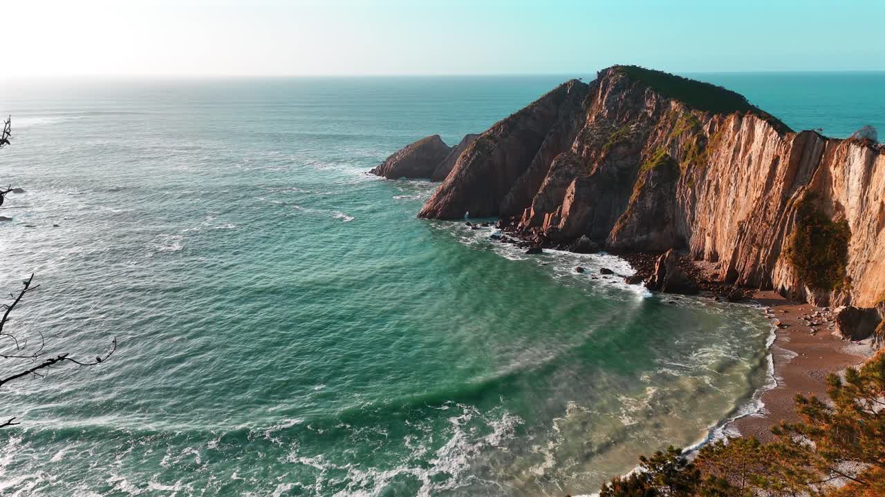 Luce solare intensa su scogliere a picco e acqua turchese lungo la costa spagnola