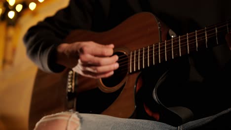 man plays the guitar and sings songs in a tent with light bulbs