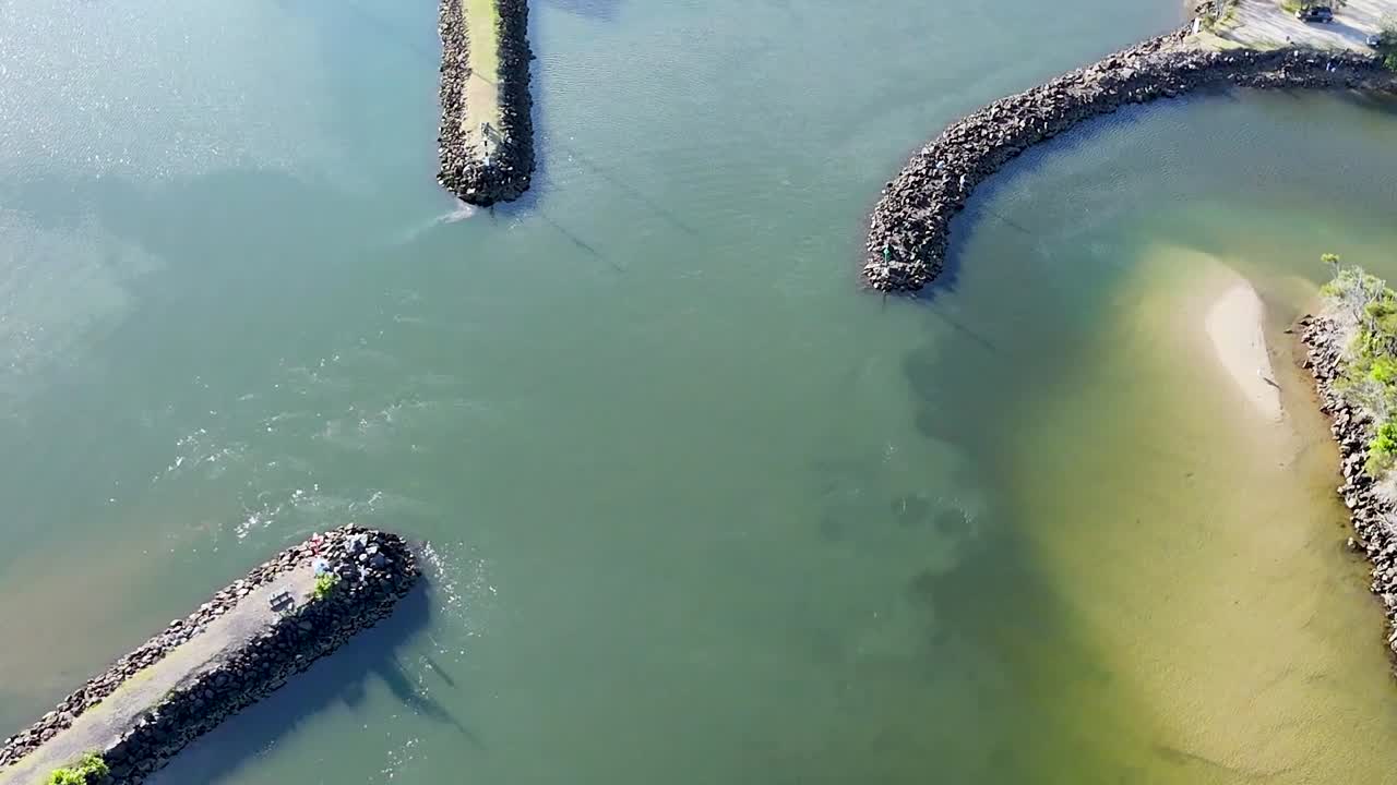 Aerial footage showcasing curved stone jetties and a tranquil waterway with a small boat.