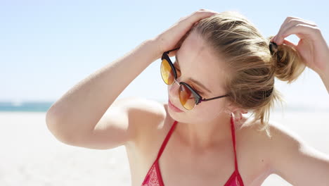 Close-up-portrait-of-beautiful-young-teenage-girl-tying-up-hair-on-windy-day-on-tropical-beach-slow-motion