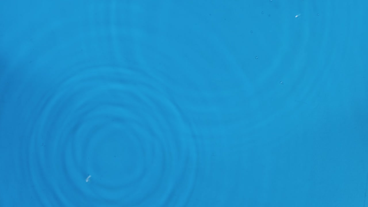 두 방울의 비가 파란 물에 떨어집니다. 위쪽 뷰. 방울은 물에 떨어지고 물의 분산하는 원으로 떨어집니다.