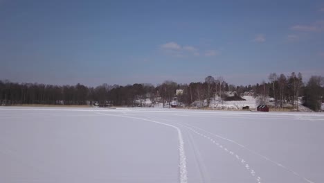 Overhead-follow-footage-of-lonesome-blonde-girl-slowly-walking-on-frozen-lake-on-a-crisp-winter's-day