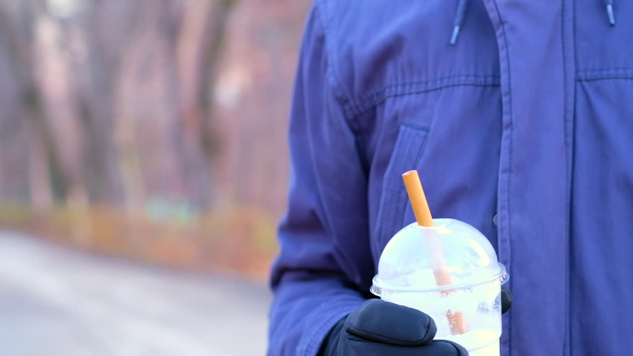Man's hand removing the bamboo straw from the coffee and throw the cup in the garbage
