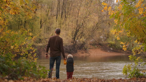 harmony of nature and unity with human father and little son are viewing wildlife of lake flying birds rear view of people weekend rest in woodland