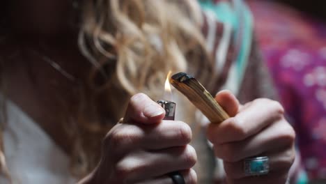 woman setting a piece of wood on fire using a lighter