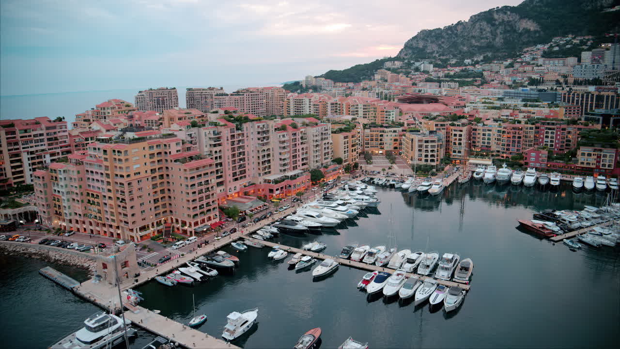 Aerial view of boats docked in the Port de Fontvieille with the skyline of Monaco on the background in the evening