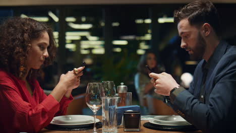 Multiethnisches-Paar,-Das-In-Einem-Schicken-Restaurant-Eine-SMS-Mit-Dem-Handy-Schreibt.-Abendessen-Date-Konzept