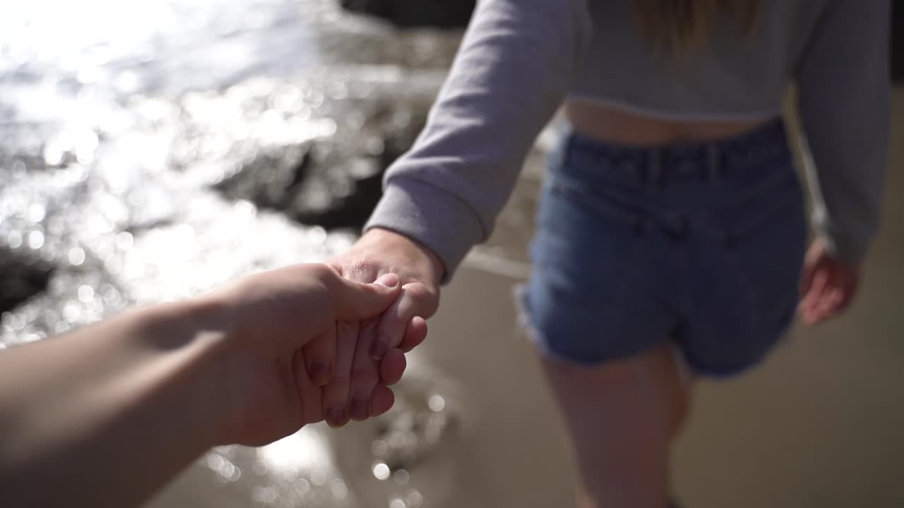 Holding a girls hand walking on a pretty beach.