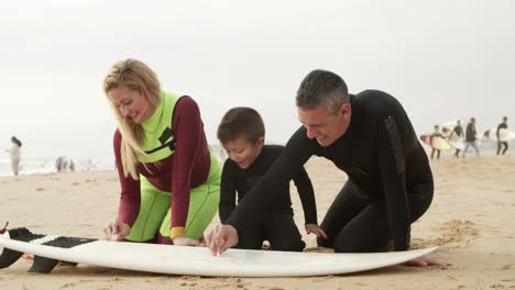 happy family waxing surfboard on beach