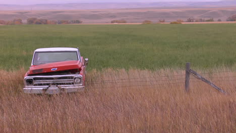 an abandoned pickup truck sits in a field