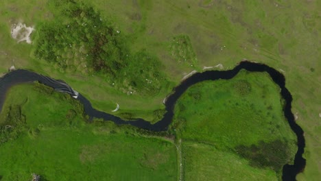 overhead drone view of kiteboarder navigating winding canal through lush terrain