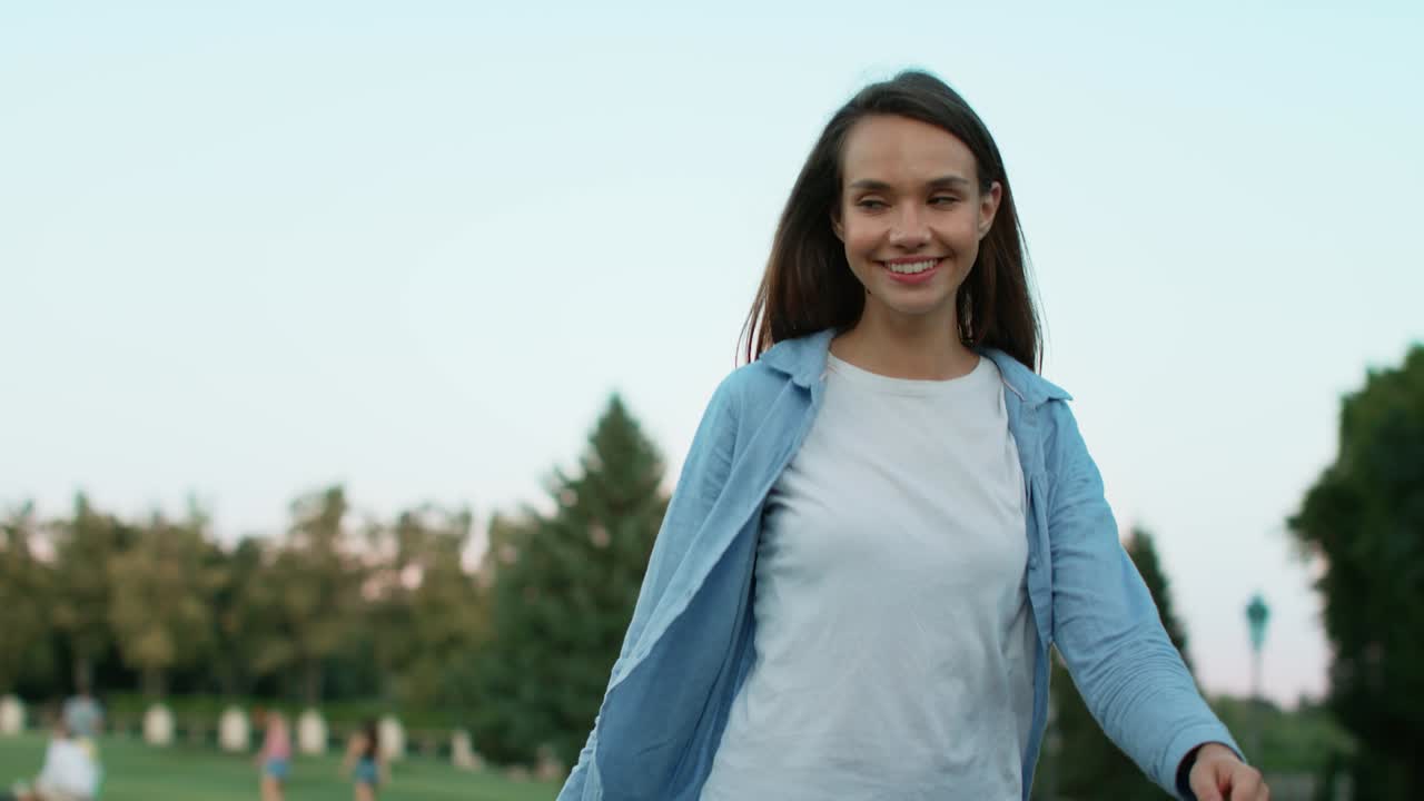 Mujer sonriente con bolsa de compras caminando en un parque de verano. Mujer feliz