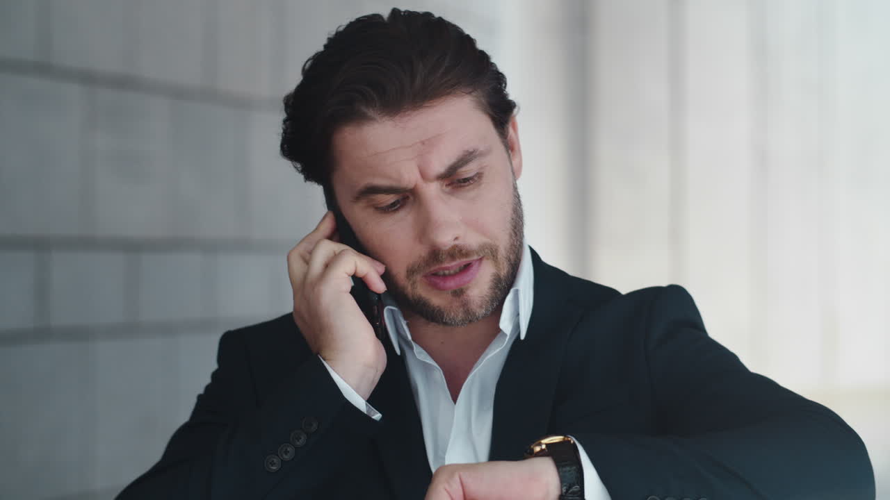 Business man having phone conversation. Executive checking time on wristwatch