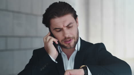 Business-man-having-phone-conversation.-Executive-checking-time-on-wristwatch