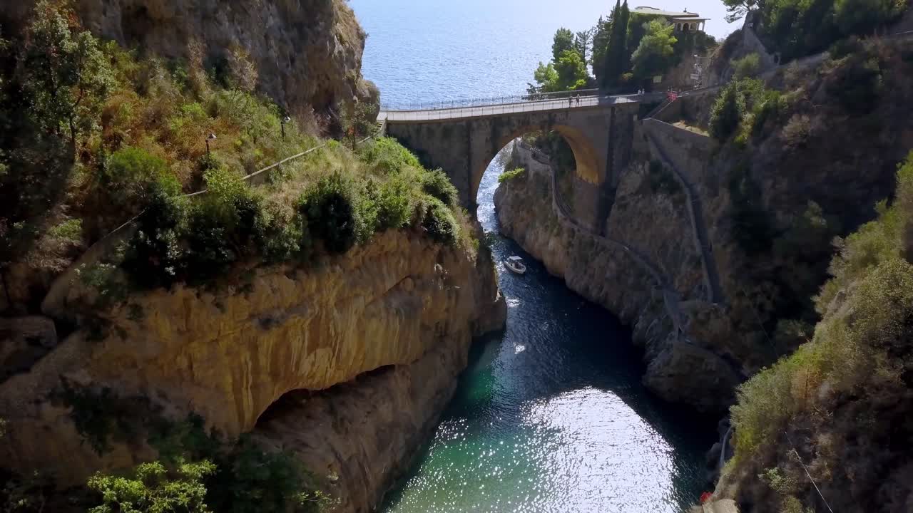 puente de arco fiordo di furore con un barco entrando en el pasaje a la aldea, costa de amalfi en salerno italia, tiro de acercamiento aéreo