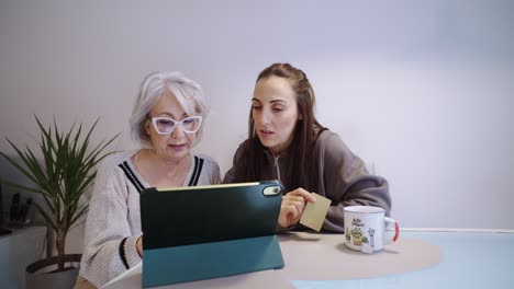 two women shopping online with a tablet and credit card