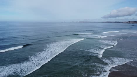 drone circles above the line up in la palue bay in brittany in france, many surfers in the waves