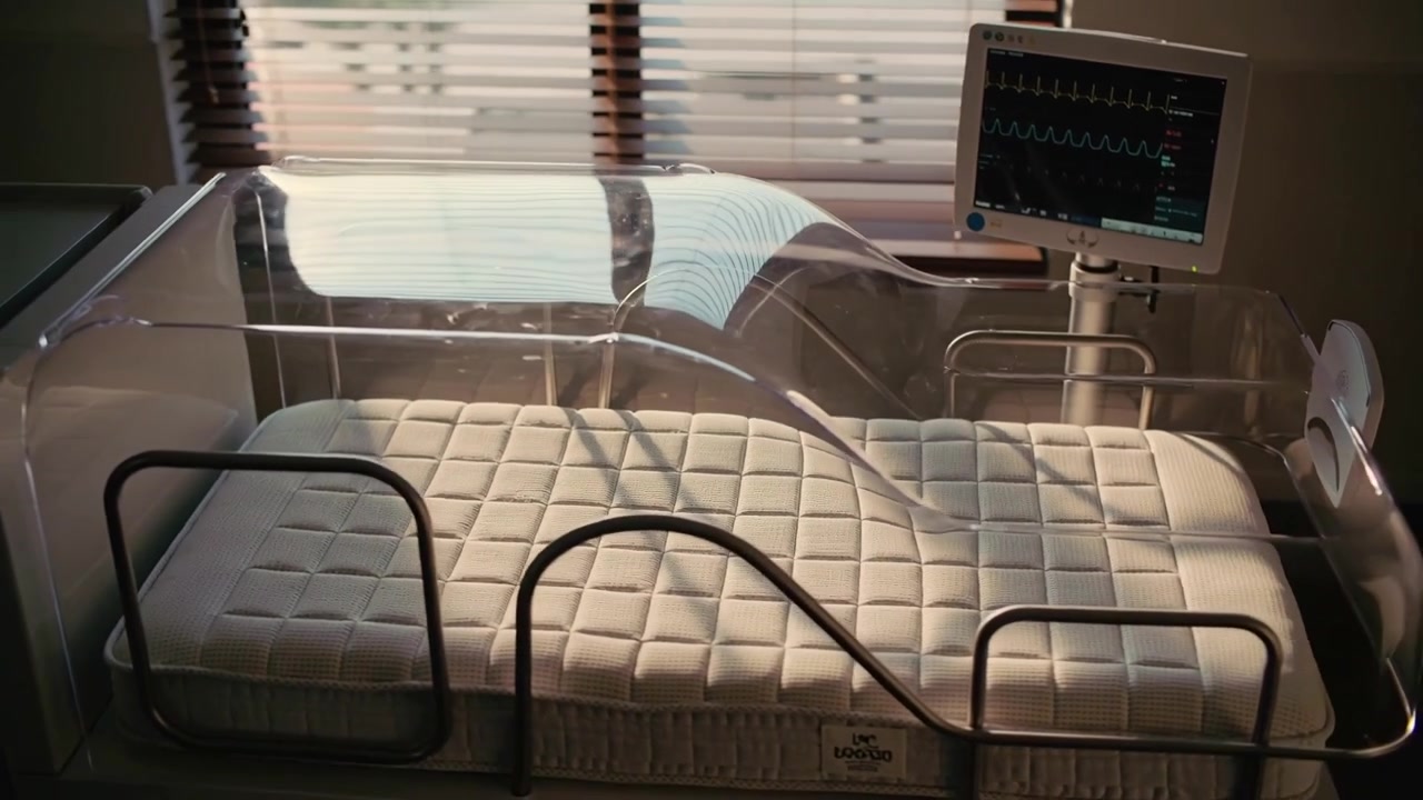Moving camera showing neonatal bassinet reflecting blinds on mattress in nursery monitor tracing