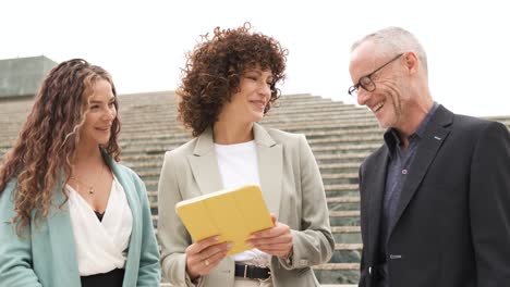 Smiling coworkers with tablet discussing project near steps