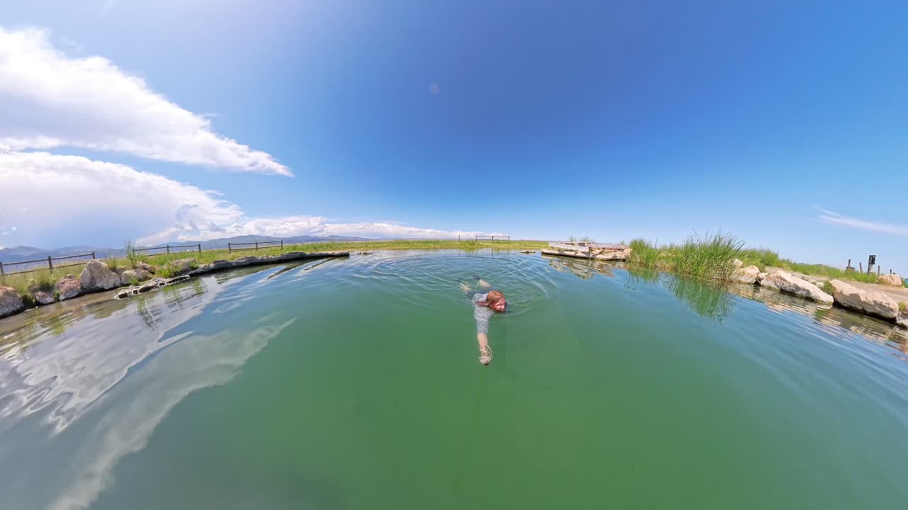 Hot Spring in Utah with a red haired male jumping in and swimming