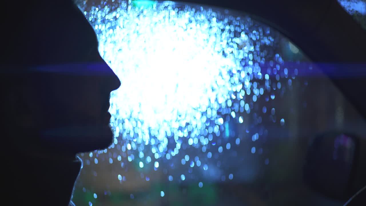 비가 오는 저녁에 차에 앉아 있는 매력적인 남자