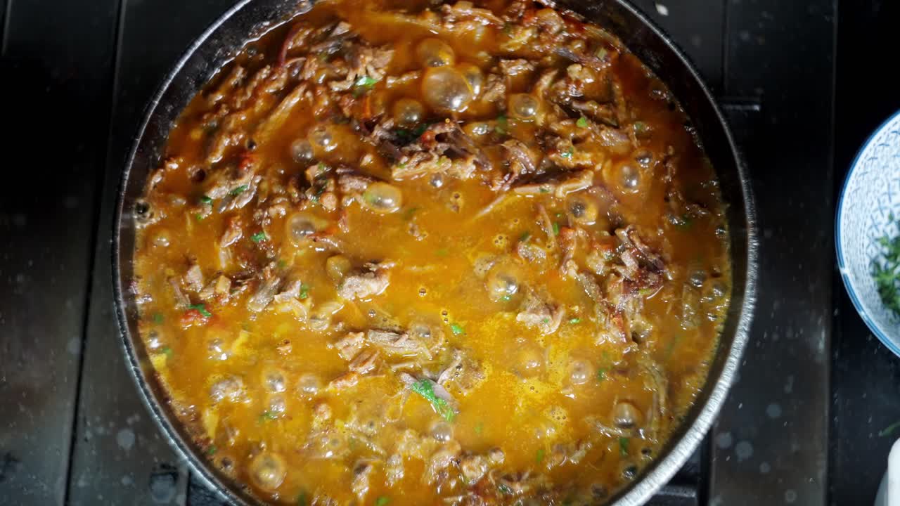 Top view down Close up in slow motion of a Bubbly and hot beef with vegetables stew in a smoky pan.