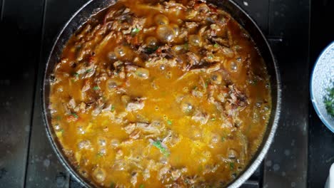 top view down close up in slow motion of a bubbly and hot beef with vegetables stew in a smoky pan.