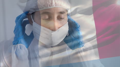 프랑스 국기가 보호복을 입은 여성 과학자를 향해 흔들리고 있습니다.