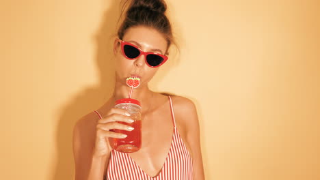 woman enjoying a drink in a striped swimsuit