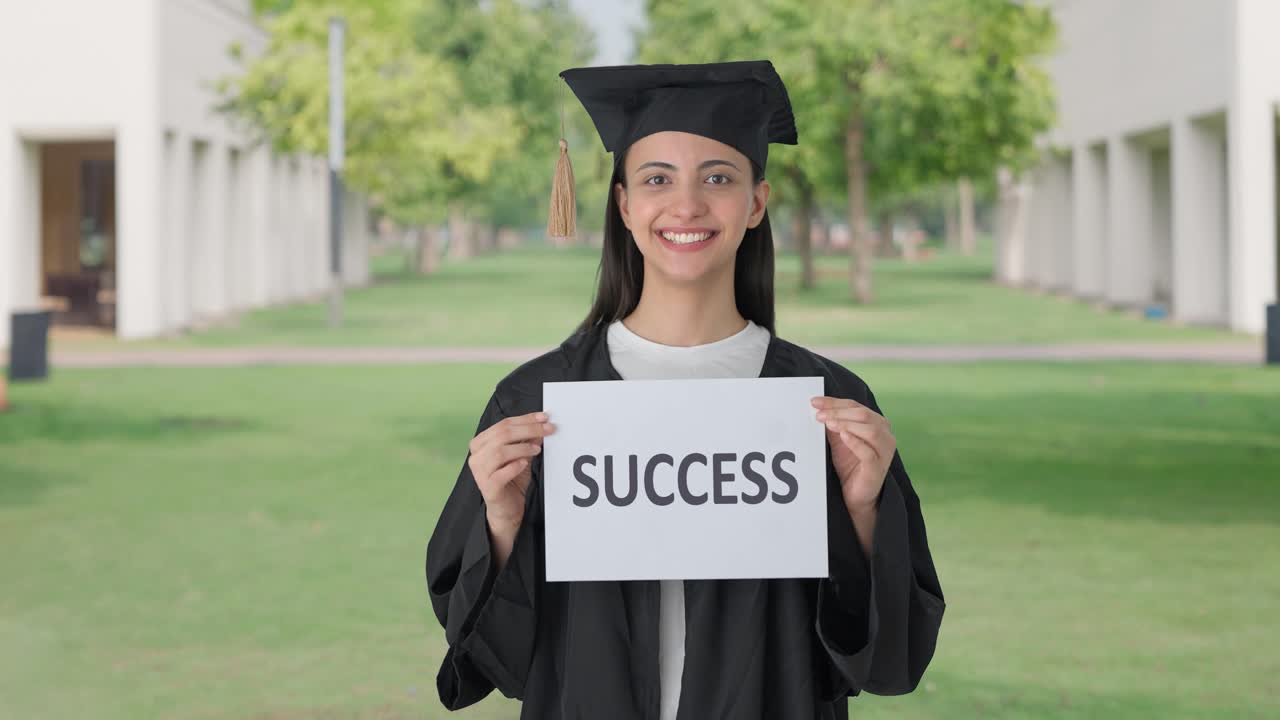 Felice ragazza indiana laureata che tiene uno striscione con scritto "SUCCESS"