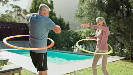 senior couple exercising with hula hoops by the pool