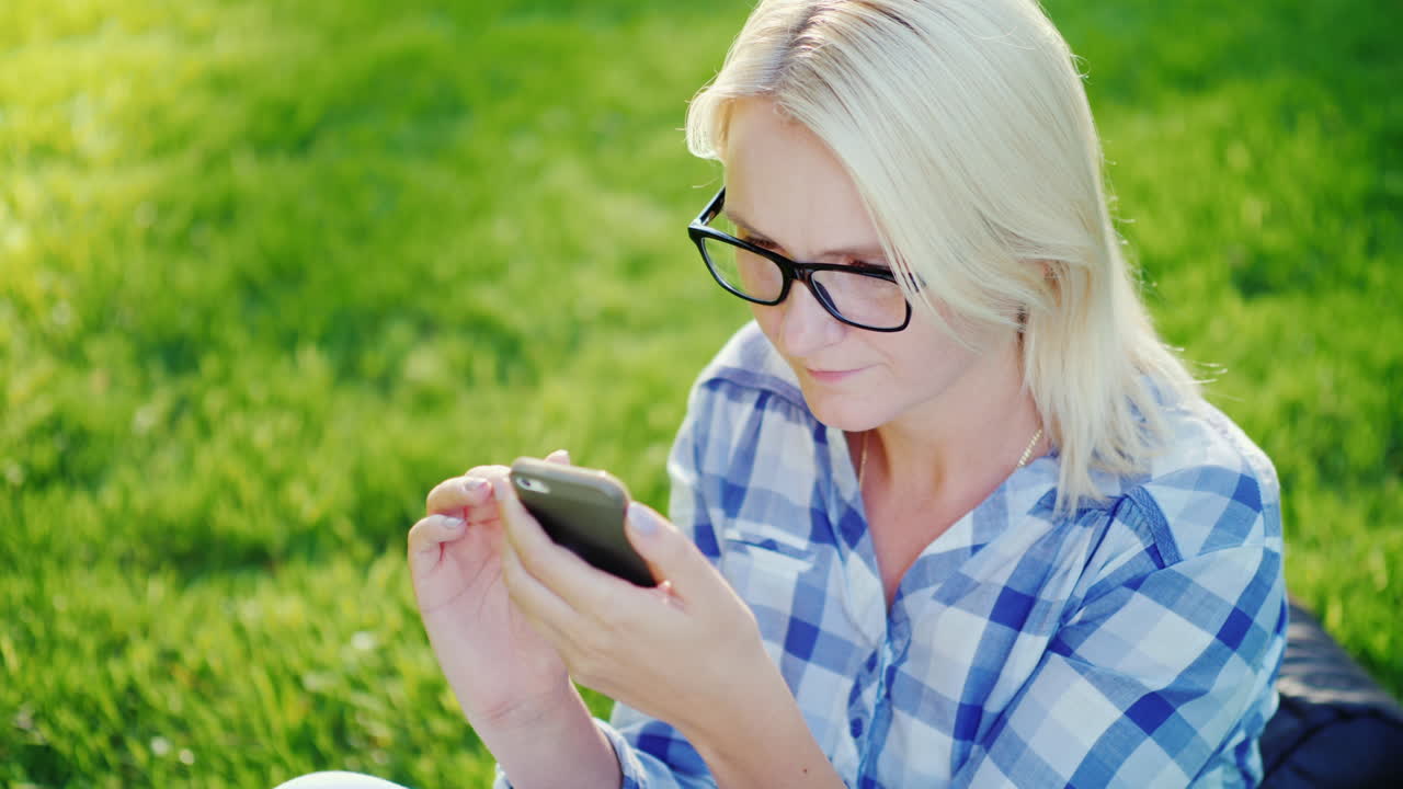 Portrait Of A Young Woman Wearing Glasses Enjoying A Smartphone In The Park Beautiful Sun Glare 4k S