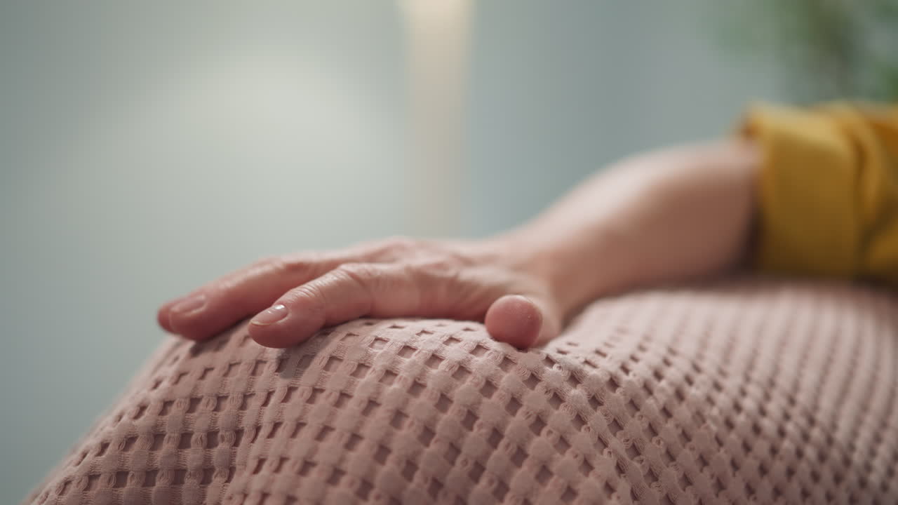 ⁇ 은 여자가 부드러운 분홍색 플레이드 위에 손을  ⁇ 고 있습니다.