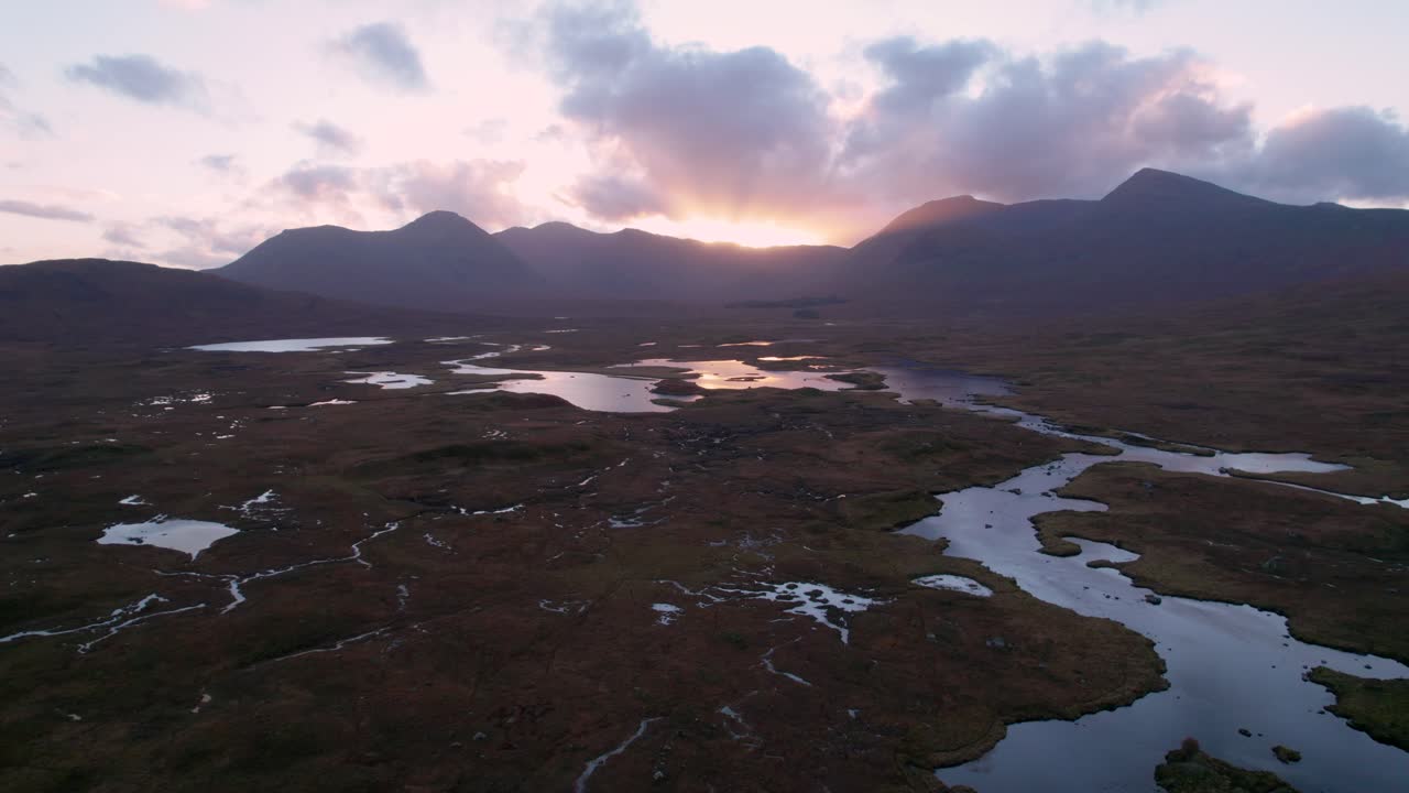 imágenes de drones de un paisaje de humedales de islas y turberas rodeadas de agua dulce mirando hacia las montañas en el horizonte al atardecer