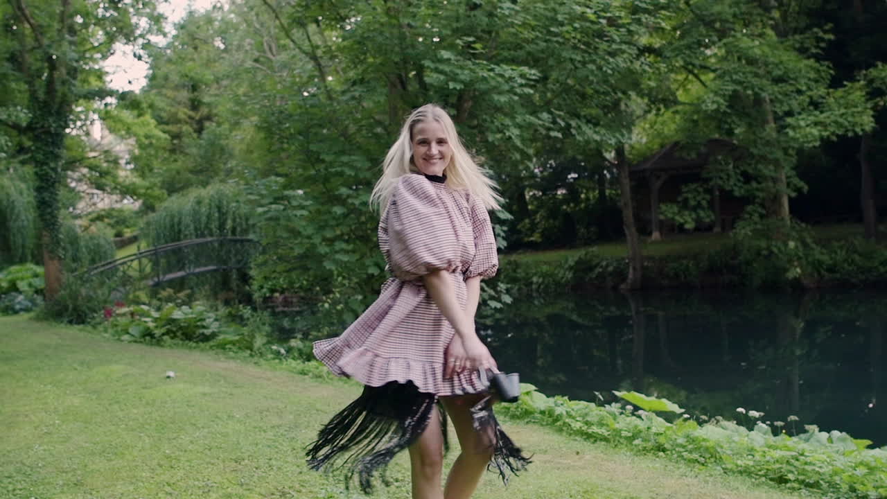 Blond woman spinning circles barefoot on grass field, enjoy life concept, slow motion