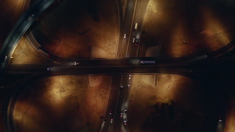 takeoff up over large roundabout or road transport junction at night with car traffic, aerial top view