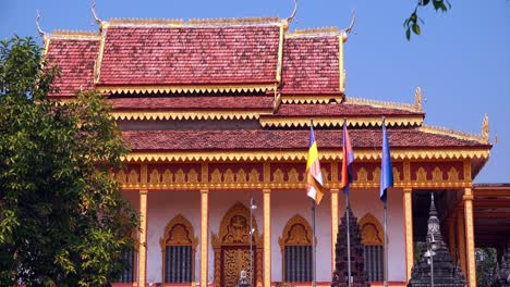 Lapso-De-Tiempo-Exterior-Medio-De-Tres-Banderas-Con-Muy-Poco-Viento-Fuera-De-Una-Pagoda-Con-Puertas-Doradas-Y-Marcos-De-Ventanas-Durante-El-Día