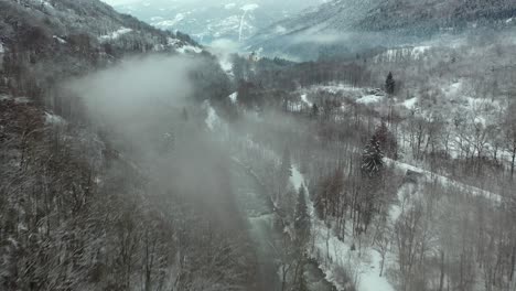 aerial: winter misty river scene in snowy mountainside valley, french alps