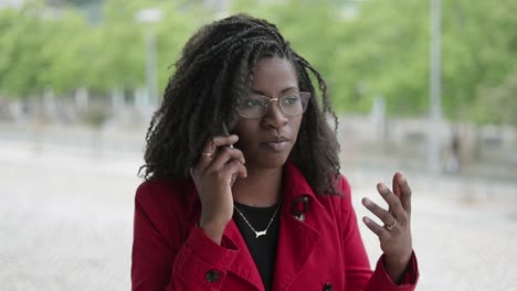 Afro-american-woman-talking-on-phone-outside,-looking-serious