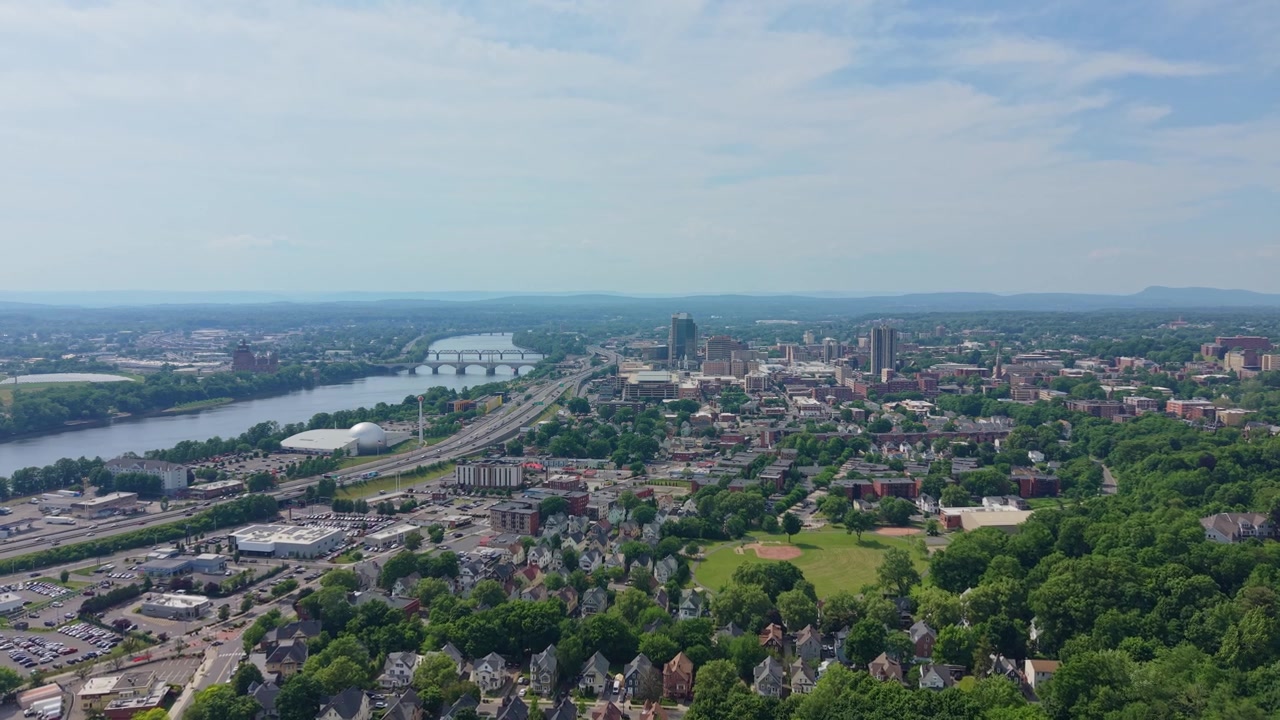Ripresa aerea distante dello skyline della città di Springfield che si estende lungo il fiume Connecticut, con l'autostrada 91 e ponti che attraversano quartieri alberati in estate, Massachusetts, USA.