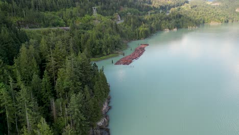 Aerial-view-of-Howe-Sound-Coastline-with-logging-lumber-floating,-Squamish,-BC,-Canada