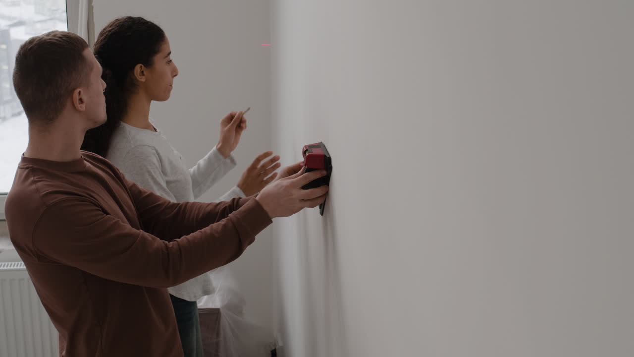 Couple Working Together on Home Improvement Project Using Laser Level