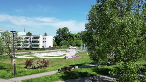 sunny day at an urban skatepark next to apartment buildings with a bus passing by.