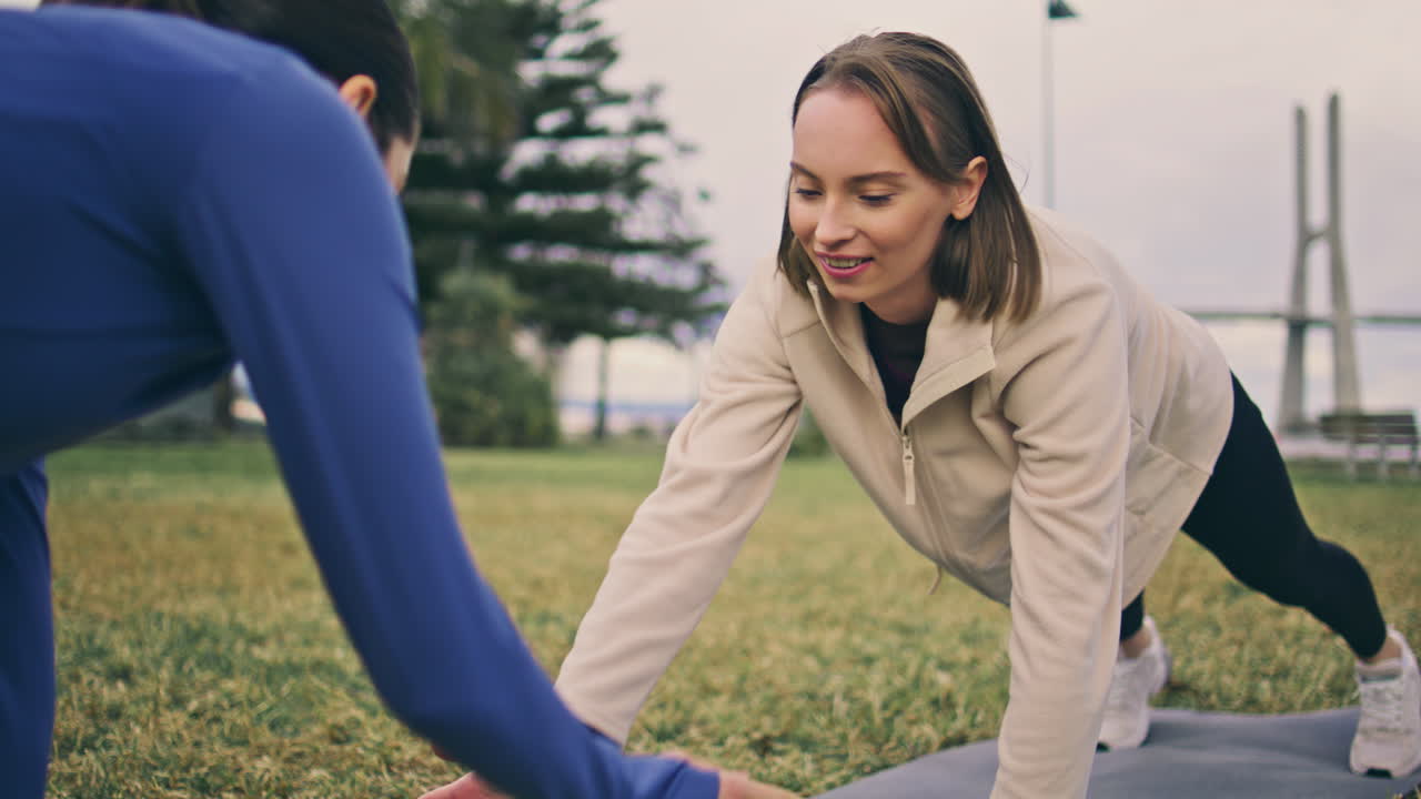 Strong athletes holding plank at glade. Young active girls high fives exercising