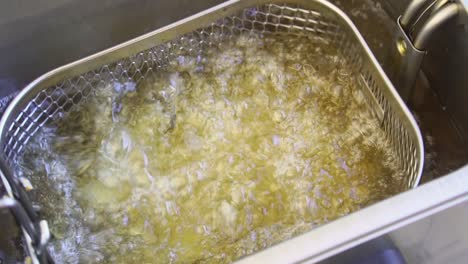 thick cut chips being dunked into deep fat fryer