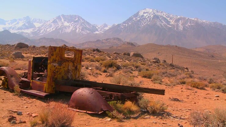 Abandoned pickup truck with the snowcapped Sierra Nevada mountains with the sun shining through clouds 1