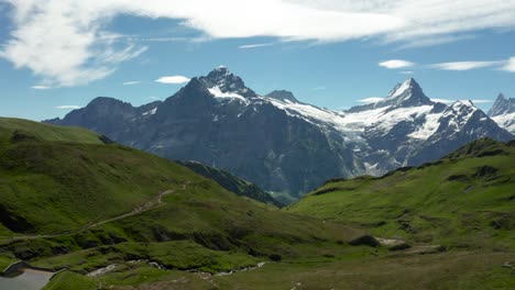 vista aérea de hermosos paisajes montañosos con picos montañosos cubiertos de nieve y hierba verde durante el verano